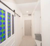 Chodba s vitrážovými dveřmi, věšáky a dřevěným dekorem v 2pokojovém bytě.