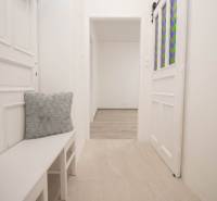 Světlá chodba s bílým nábytkem a dekorativními polštáři v 2pokojovém bytě.