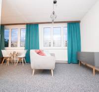 Obývací pokoj ve 4pokojovém bytě s modrými závěsy a šedým nábytkem.