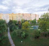 Velký bytový dům obklopený stromy a udržovanými chodníky na Krakovské v Košicích.