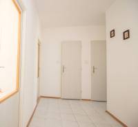 Chodba se světlými stěnami a bílými dveřmi ve 4-pokojovém bytě.