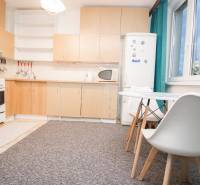 Kuchyně s bílým nábytkem a jídelním stolem ve 4-pokojovém bytě.