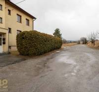 Exteriér 5 a více pokojového bytu ve Staré Lesné s viditelnými keři a cestou.