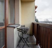 Balkon s dřevěným zábradlím a stolem se dvěma židlemi v bytě s 5 a více pokoji.