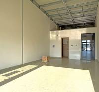 Prostorné obchodní prostory s vysokým stropem a betonovou podlahou.