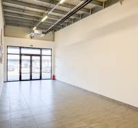 Prostorné obchodní prostory s dlažbou a velkými dveřmi.