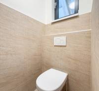 Toaleta s přírodním obkladem v obchodních prostorech, jednoduchý design a oknem.