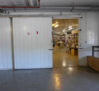 Otevřená hala se skladovaným materiálem, regály a průmyslovými dveřmi, Sklady a haly.