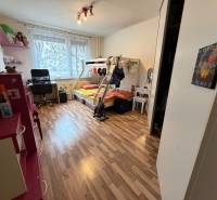 Dětský pokoj s podlahou s dřevěným dekorem, patrovou postelí a pracovním stolem.