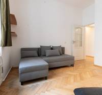 Šedá pohovka s polštáři a podlaha s dřevěným dekorem ve 4-pokojovém bytě.