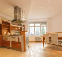 Kuchyně s jídelním koutem ve 4-pokojovém bytě, podlaha s dřevěným dekorem, bílá stěna.