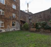 Dvůr obytného domu na Medenej ulici v Bratislavě - Staré Město s lavičkou a zelení.