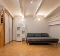 Obývací pokoj s pohovkou, schody a podlahou s dřevěným dekorem ve 4pokojovém bytě.