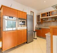 Kuchyně ve 4-pokojovém bytě s nerezovými spotřebiči a dřevěnými skříňkami.