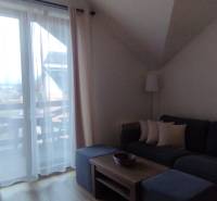 Obývací pokoj v 2pokojovém bytě s pohovkou, konferenčním stolkem a výhledem na balkon.