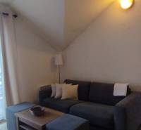 Obývací pokoj v 2-pokojovém bytě s pohovkou, konferenčním stolkem a prosklenými dveřmi na balkon.