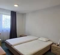 Ložnice s dvěma postelemi, psacím stolem a oknem ve 3-pokojovém bytě.