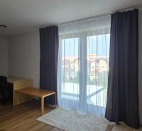 Obývací pokoj se stolem a podlahou s dřevěným dekorem ve 3-pokojovém bytě.