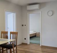 Jídelní stůl se židlemi a podlaha s dřevěným dekorem v 3-pokojovém bytě.