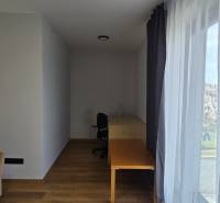 Pokoj v 3-pokojovém bytě s podlahou s dřevěným dekorem, stolem a pohovkou.