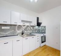 Kuchyně v 1-pokojovém bytě s bílým nábytkem a podlahou s dřevěným dekorem.