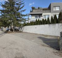 Garáže na Vavřínové ulici v Bratislavě - Ružinově s okolní zelení a domy.