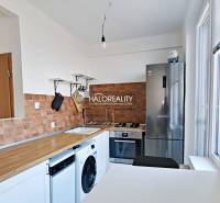 Kuchyně ve 3-pokojovém bytě s podlahou s dřevěným dekorem a spotřebiči.