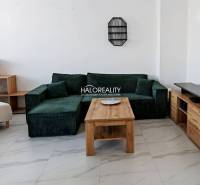 Obývací pokoj v 3-pokojovém bytě se zelenou sedačkou a dřevěným stolem.