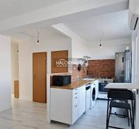 Kuchyně v 3-pokojovém bytě s bílou linkou, spotřebiči a dřevěným dekorem.