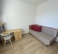 Obývací pokoj ve 4-pokojovém bytě se stolem, židlí a pohovkou. Podlaha s dřevěným dekorem.