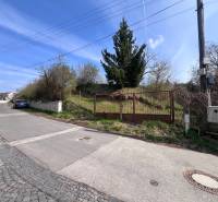 Pozemek na bydlení na Budovatelské ulici v Mariance s bránou a příjezdovou cestou.