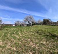 Pozemky k bydlení na Budovatelské ulici v Mariance, obklopené zelení a stromy.