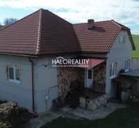 Rodinný dům v Rimavských Janovcích s červenou střechou a venkovským okolním prostředím.