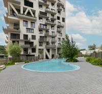 Bytový komplex s bazénem na ulici Polianky v Bratislavě, Dúbravka, obklopený zelení.