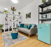 Stylový obývací prostor v 1-pokojovém bytě s podlahou s dřevěným dekorem, dekoracemi a rostlinami.