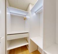 Vestavěná skříň se světlým interiérem a podlahou s dřevěným dekorem v 1-pokojovém bytě.