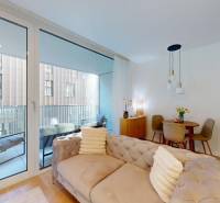 Obývací prostor v 1-pokojovém bytě s balkonem, pohovkou a kuchyňským stolem.