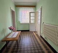 Chodba v rodinném domě s květinami na stole a kachličkovou podlahou.