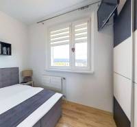 Ložnice s postelí a televizorem, podlaha s dřevěným dekorem v 3-pokojovém bytě.