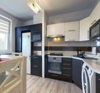 Kuchyně v 3-pokojovém bytě s linkou a spotřebiči, podlaha s dřevěným dekorem.