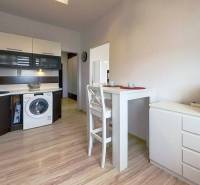 Kuchyně ve 3-pokojovém bytě s jídelním stolem a podlahou s dřevěným dekorem.