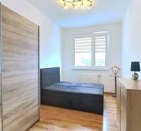 Světlá ložnice v 3pokojovém bytě s podlahou s dřevěným dekorem a velkou skříní.