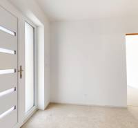 Vstupní dveře s prosklením v interiéru rodinného domu s bílými stěnami.