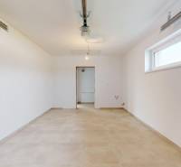 Priestranná místnost se světlými stěnami a oknem v rodinném domě, podlaha s dekorem.