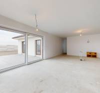 Rodinný dům s prostorným obývacím pokojem, velkým oknem a výhledem na terasu.