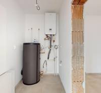 Topení a bojler v technické místnosti rodinného domu s dlažbou na podlaze.