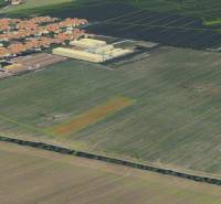 Práznovce z ptačí perspektivy, zemědělské a lesní pozemky obklopující obytnou oblast.