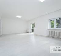 Prostorný obývací pokoj ve 4pokojovém bytě s bílou podlahou a velkými okny.