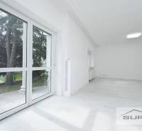 Světlý pokoj s velkými okny a podlahou s dřevěným dekorem ve 4-pokojovém bytě.