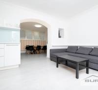 Obývací pokoj čtyřpokojového bytu s kuchyňským koutem a sedací soupravou.